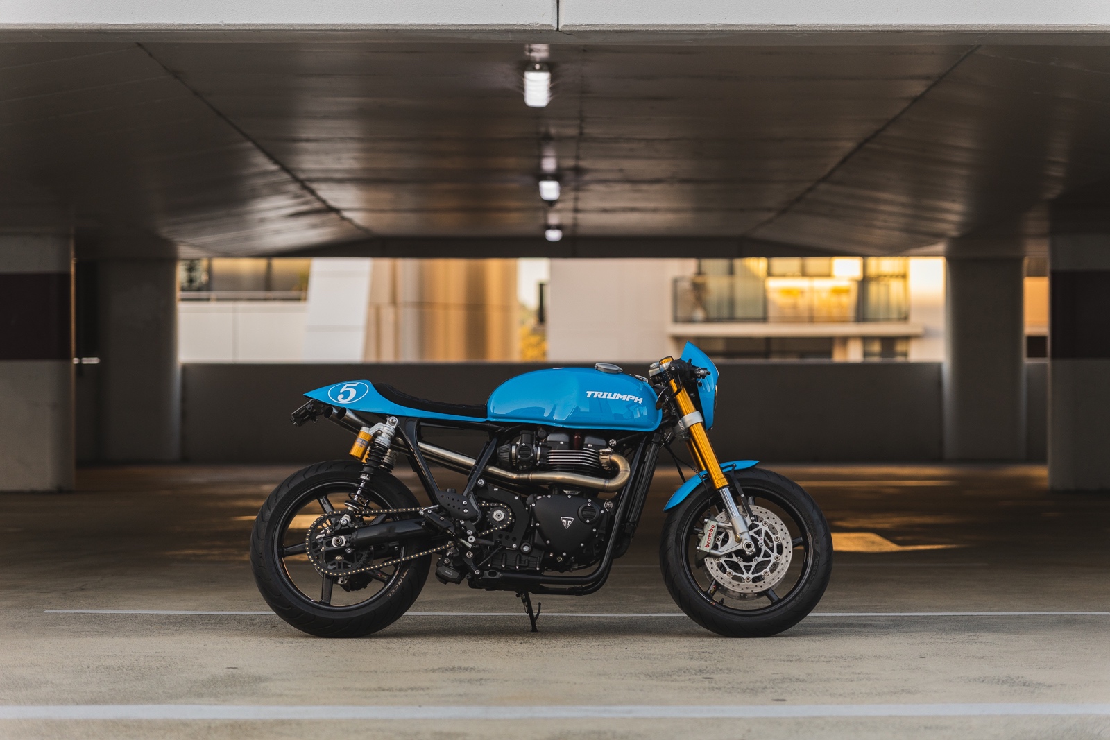 Side view photo of a Triumph Thruxton R Custom Motorcycle in a parking garage